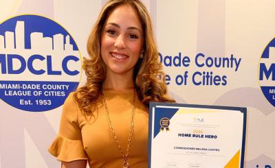 Commissioner Castro holding Home Rule Hero Award in from of Miami-Dade County League of Cities