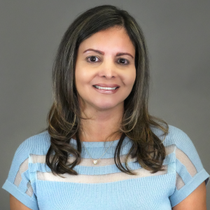 Page Perez in sky blue business shirt, smiling with gray gradient background