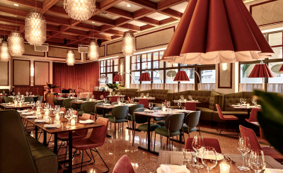 Elegant dining restaurant with warm overhead lights and dark red hues for lamps and seats